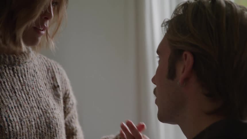 A serious moment between a blonde man who is looking intently at a woman whose hand rests gently on his shoulder