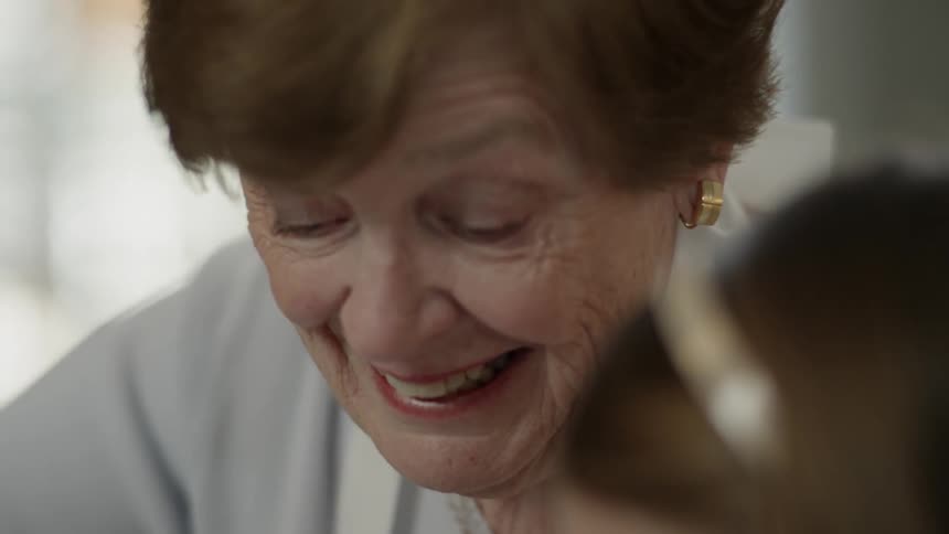 An older woman laughs and talks to a young girl