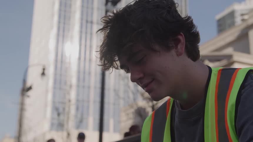 An employee wearing a high visibility vest standing outdoors in a city