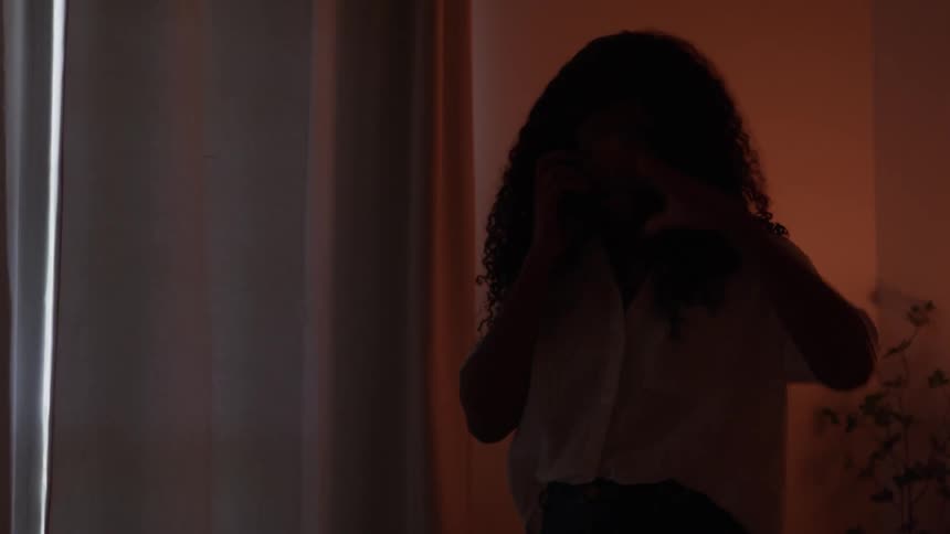 Woman standing talks on the phone in a home setting