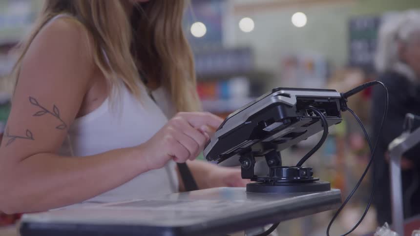 A woman uses an electric card reader to pay for her purchase at a store
