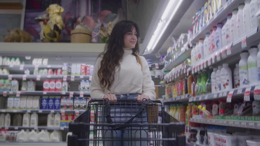 Woman pushes a cart in the grocery store looking at items on the shelves