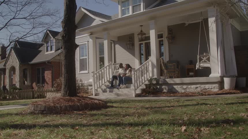 Couple sitting on the steps of their house drinking coffee and enjoying the neighborhood