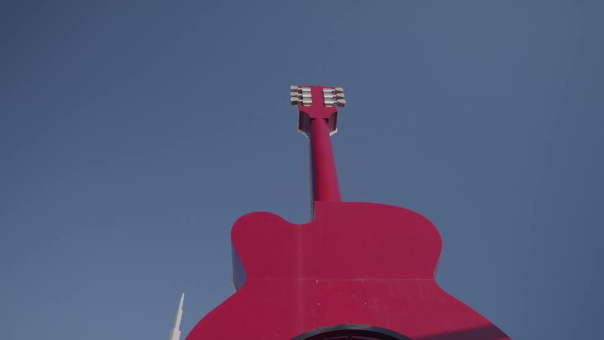 Red guitarshaped structure stands out against blue sky