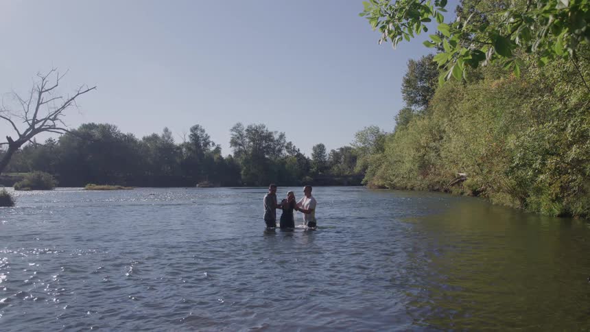 Baptism takes place in the river surrounded by calm water and trees