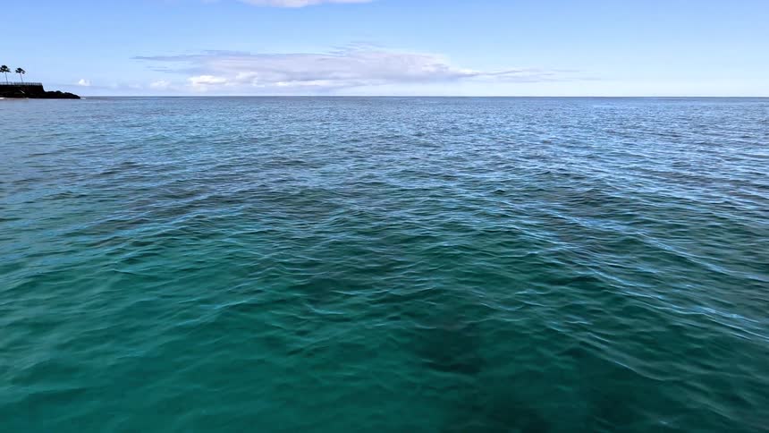 Calm sea stretches in shades of blue beneath a clear sky