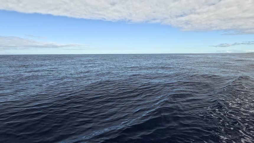 Ocean water stretches beneath partly cloudy sky