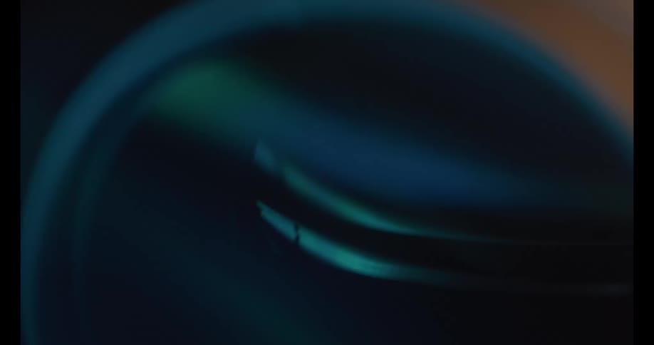 Bluish light highlights the smooth contours of a metallic object in an abstract closeup