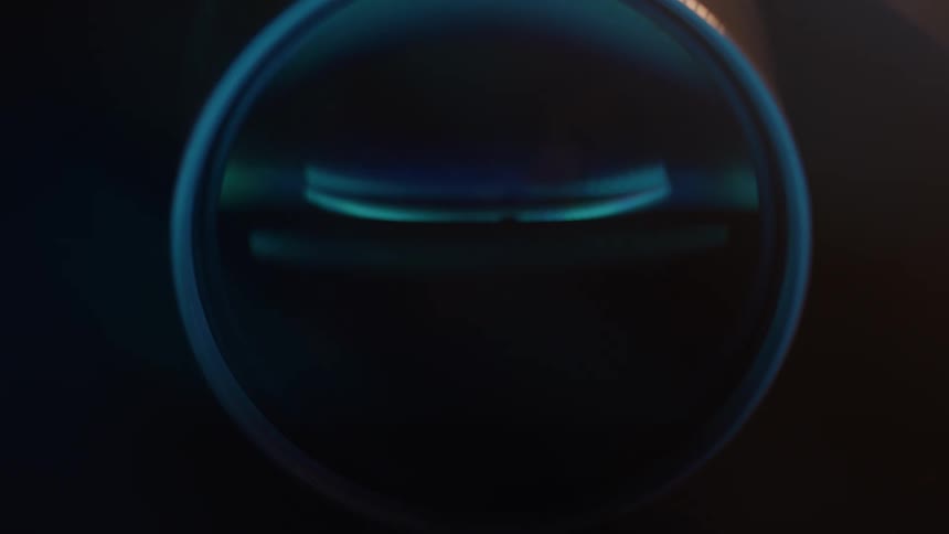 A moody abstract view focuses on the cool blue light reflecting within the glass of a camera lens