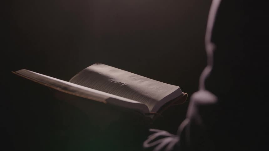 The person is reading a book in a dark room