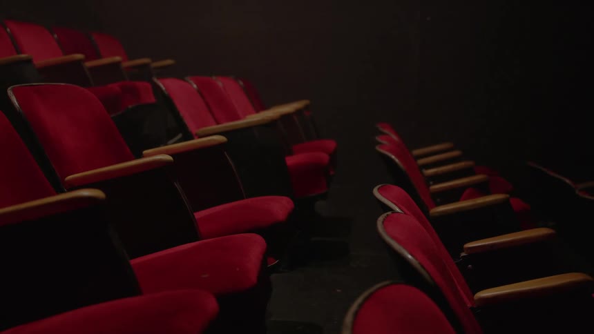 Several rows of red chairs in a completely dark room