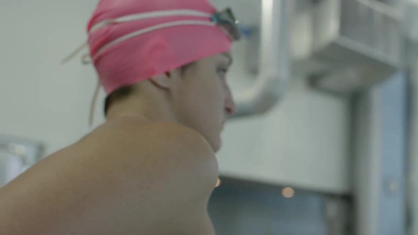 Woman stretching at an olympic sized pool wearing proper swim gear