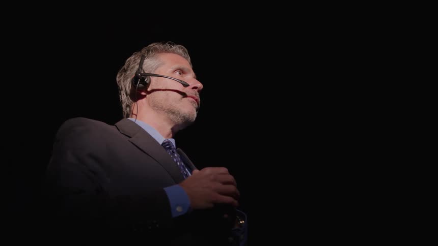 The man gives a speech under a spotlight
