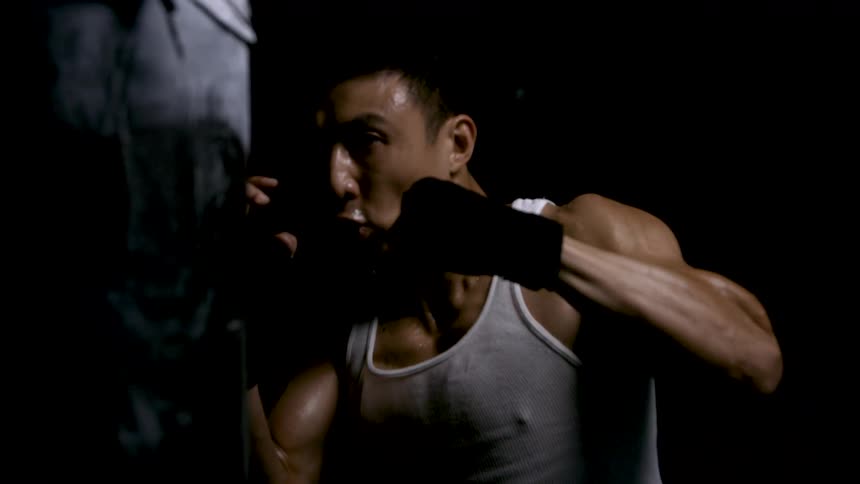 The man is punching the heavy bag hard