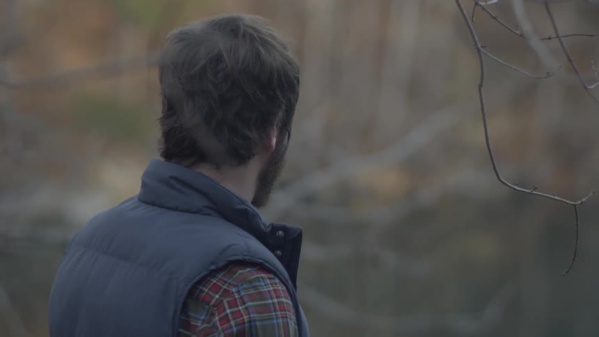 A man in a puffy vest looks around outside
