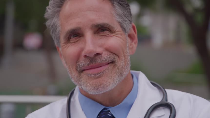 A portrait of a grayhaired man with a stethoscope slung over his shoulder looking straight ahead with a slight smile