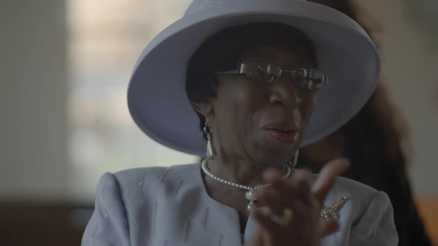 Woman wearing a hat smiles and claps her hands