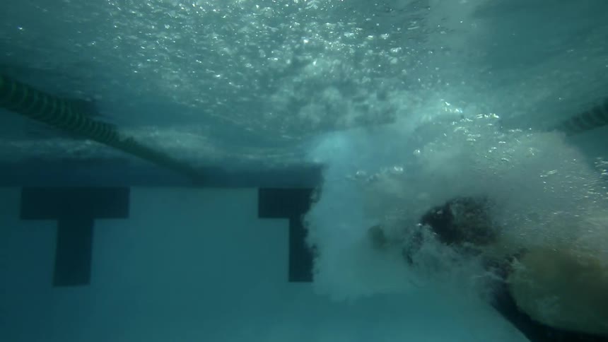 Swimmer diving into the pool as seen underwater