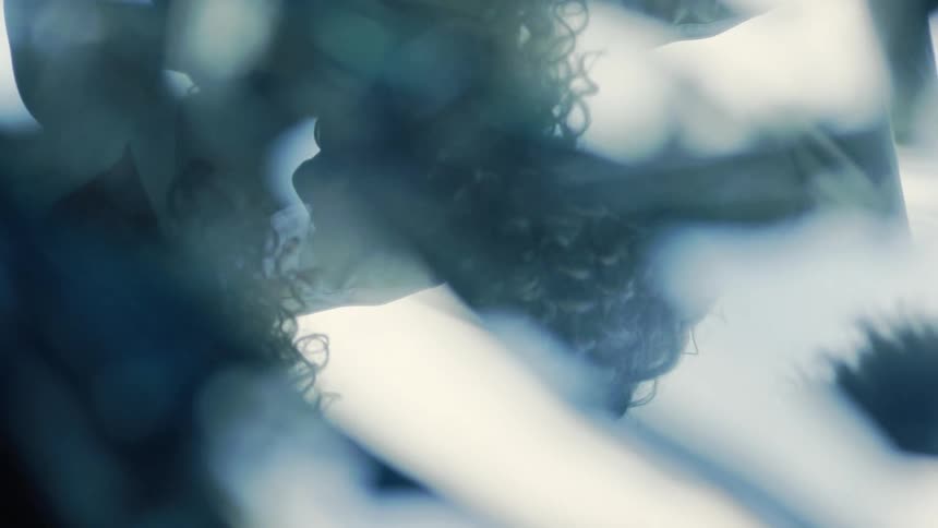 A persons reflection is seen fragmented in what appears to be shards of broken glass