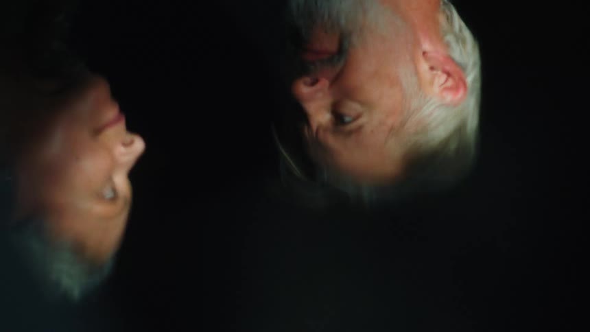 Reflection of an elderly couple lovingly blinking at each other