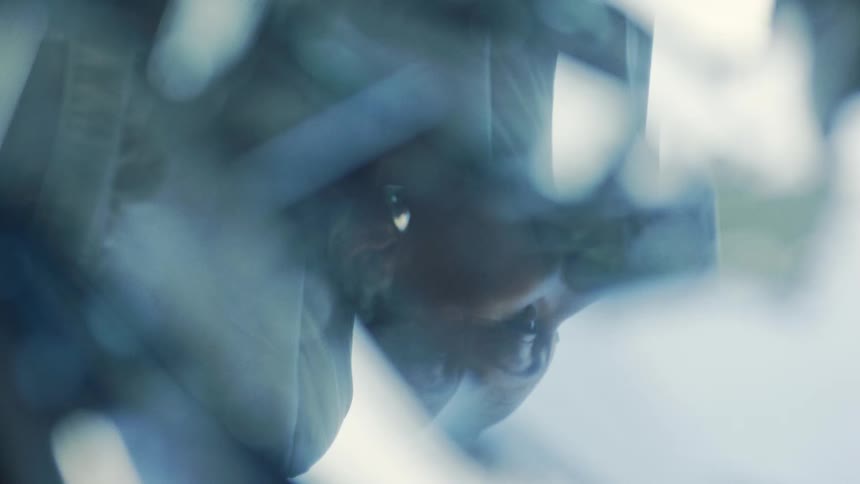 A womans face appears reflected in blurry water with soft blue highlights