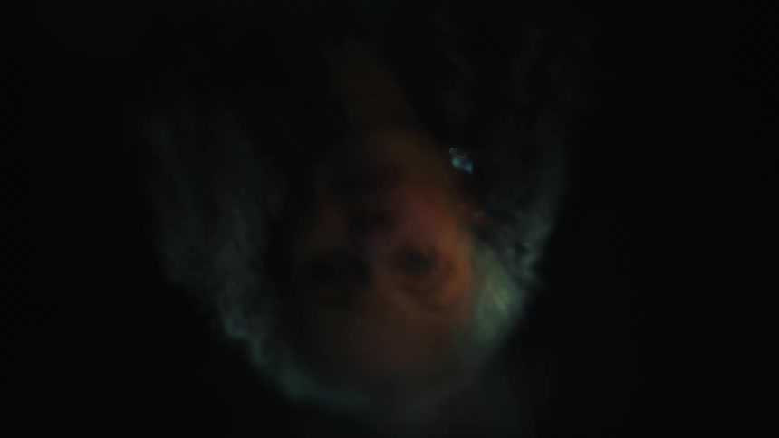 A closeup of a womans face reflected on dark water in low light