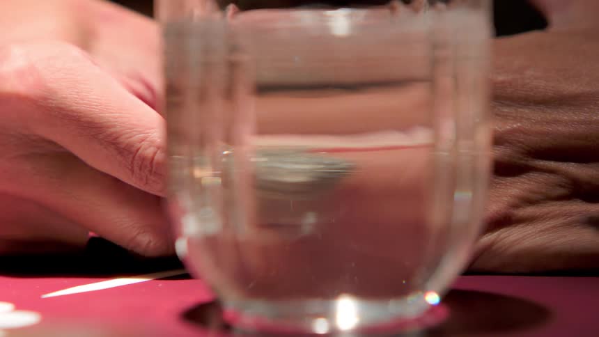 Woman sitting at a table with a drink puts her diamond wedding ring back on her finger