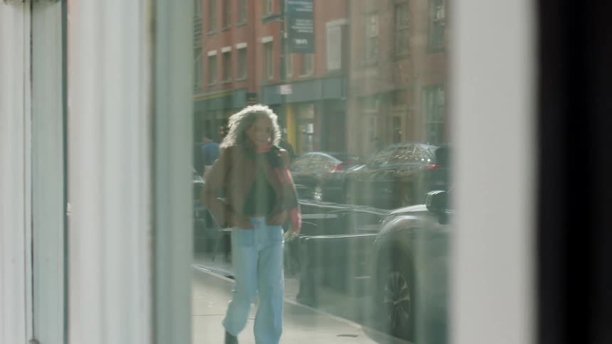 The woman walks past the building on the sidewalk