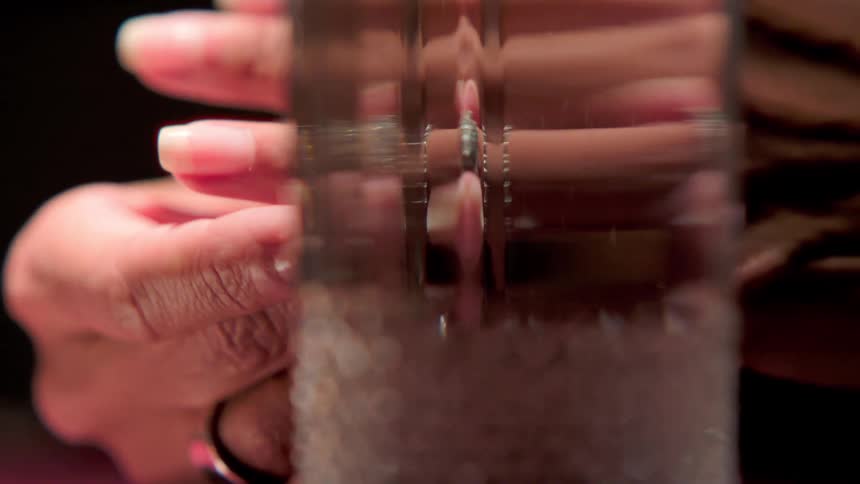 Woman sitting at a table with a drink puts her wedding ring back on her finger