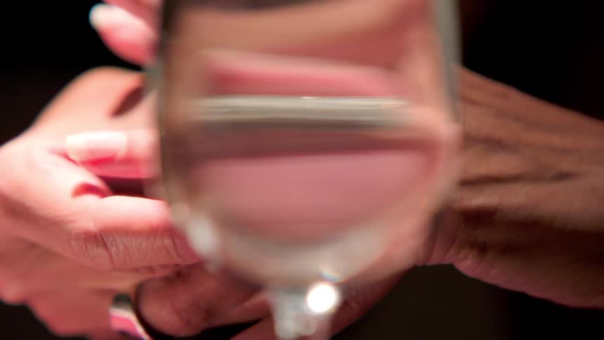 Woman sitting at a table with a drink puts her wedding ring back on her finger