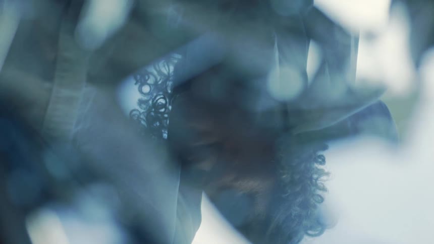 A womans reflection appears on a glass surface her curly short hair clearly visible in the mirrored image