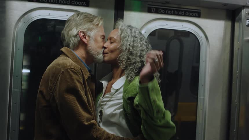 Couple kisses inside the subway while holding each other close