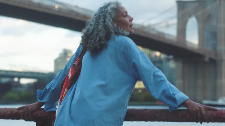 A woman walking outdoors near a bridge
