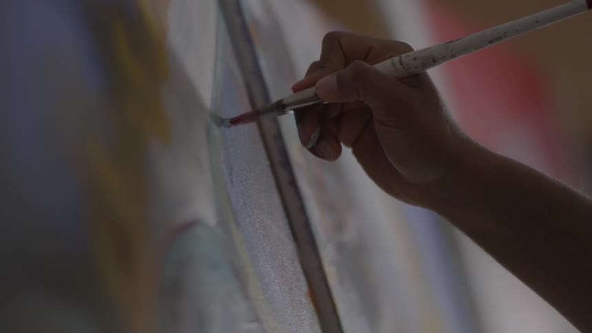 A person paints on a canvas with a brush