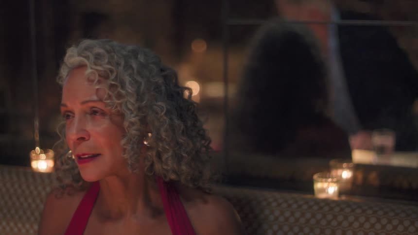The man gets up from the table in the restaurant as a woman looks at a menu