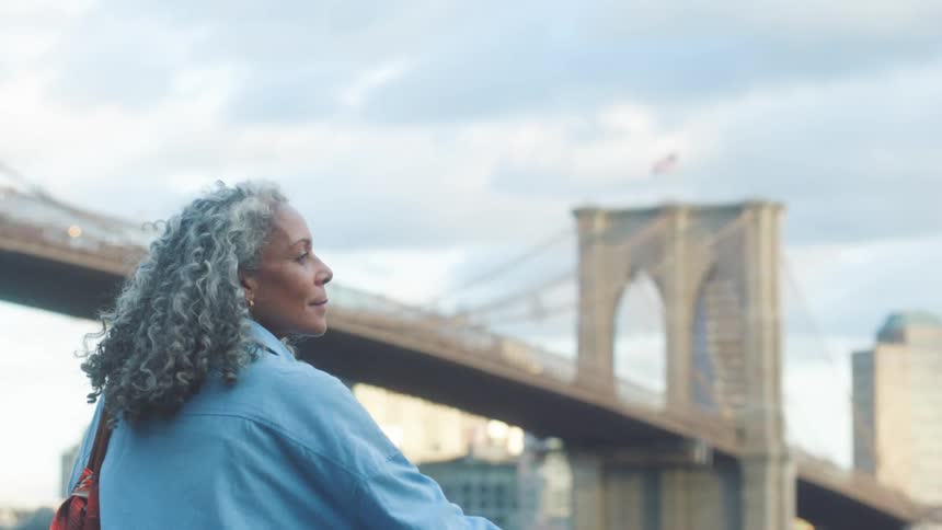 Woman looks at the scenery near the bridge under a partly cloudy sky