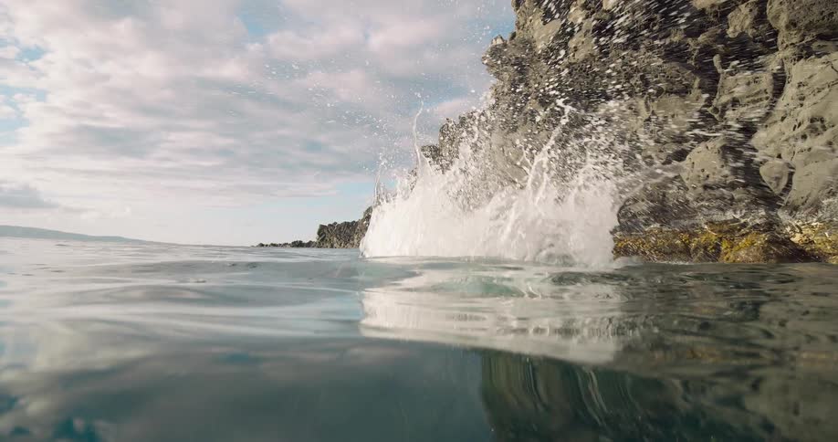 A man jumping from a high rock towards a body of water