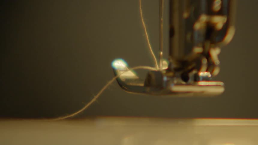 A part of a sewing machine with a thread attached moving slowly