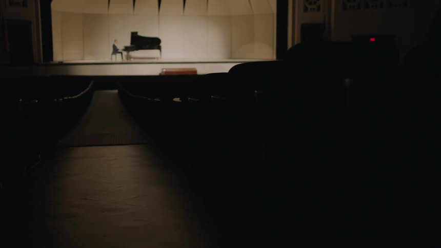 A man is playing the piano on a bright stage