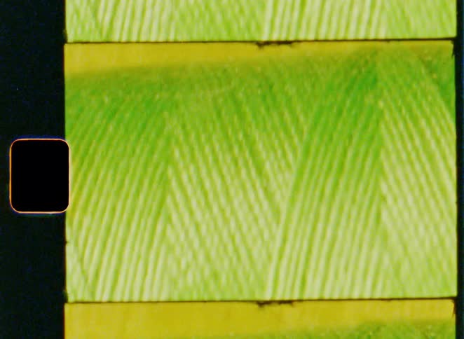 Threads in colors including oranges and blues lie in a row