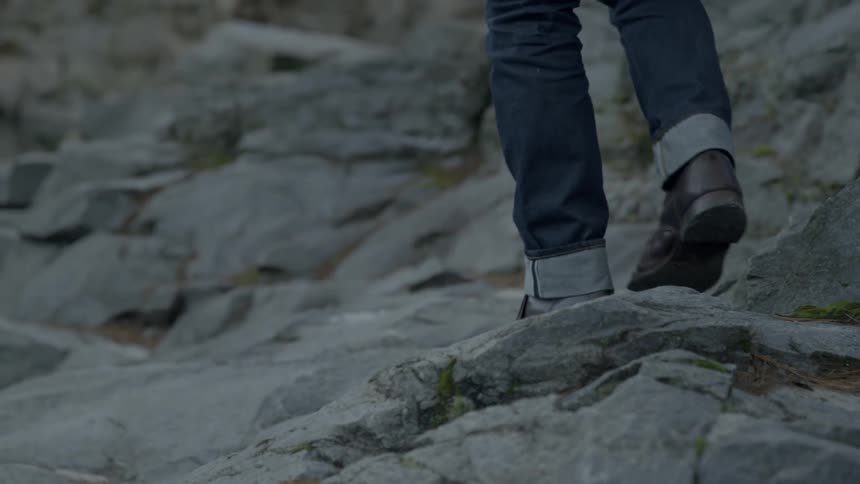 A person walks over the rocks wearing boots