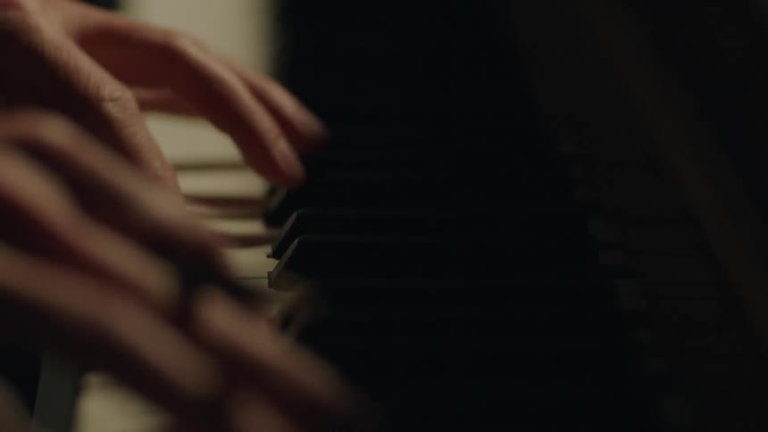 A person holding a pencil plays the piano