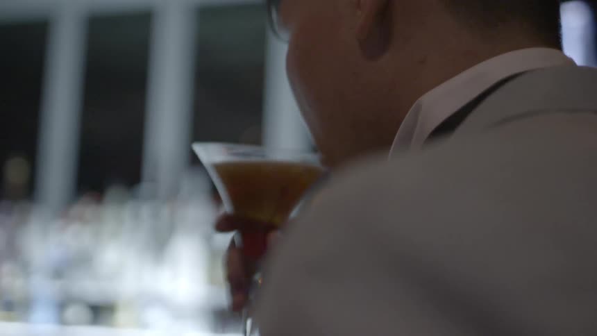 A person drinking a drink at a bar