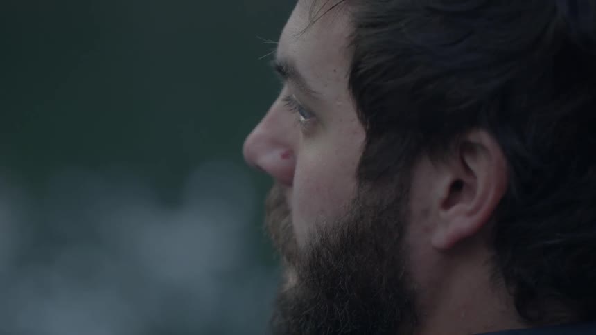 A man looks out at a forest lake
