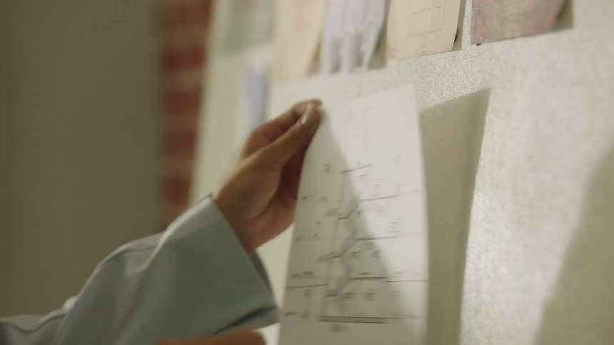 A person taking a piece of paper off a bulletin board