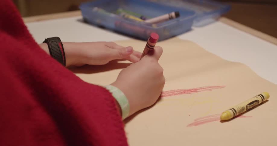 A child coloring on paper with crayons at a table