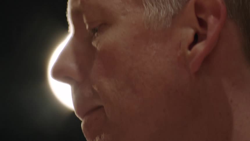An overhead light shines on a man's face