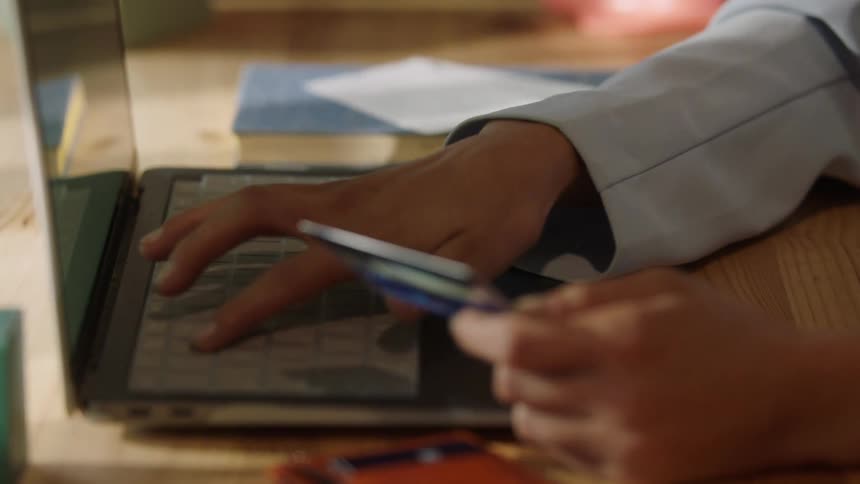 Woman holding a credit card and typing on the keyboard of a laptop computer