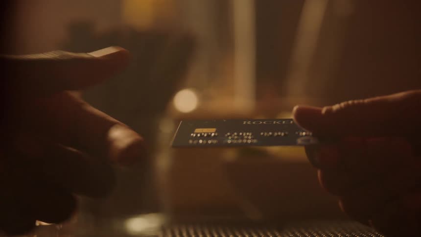 Person hands over a credit card at a bar table