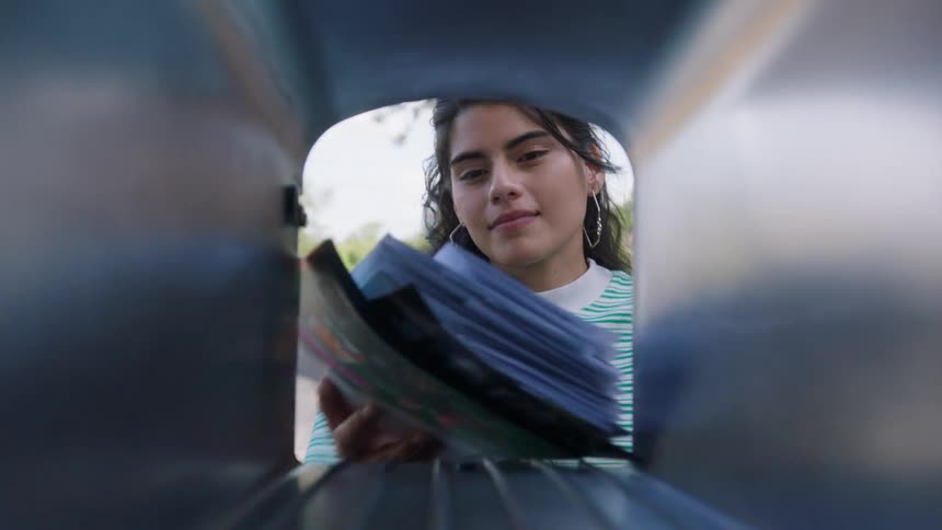 The face of a woman who is taking some letters from a mailbox